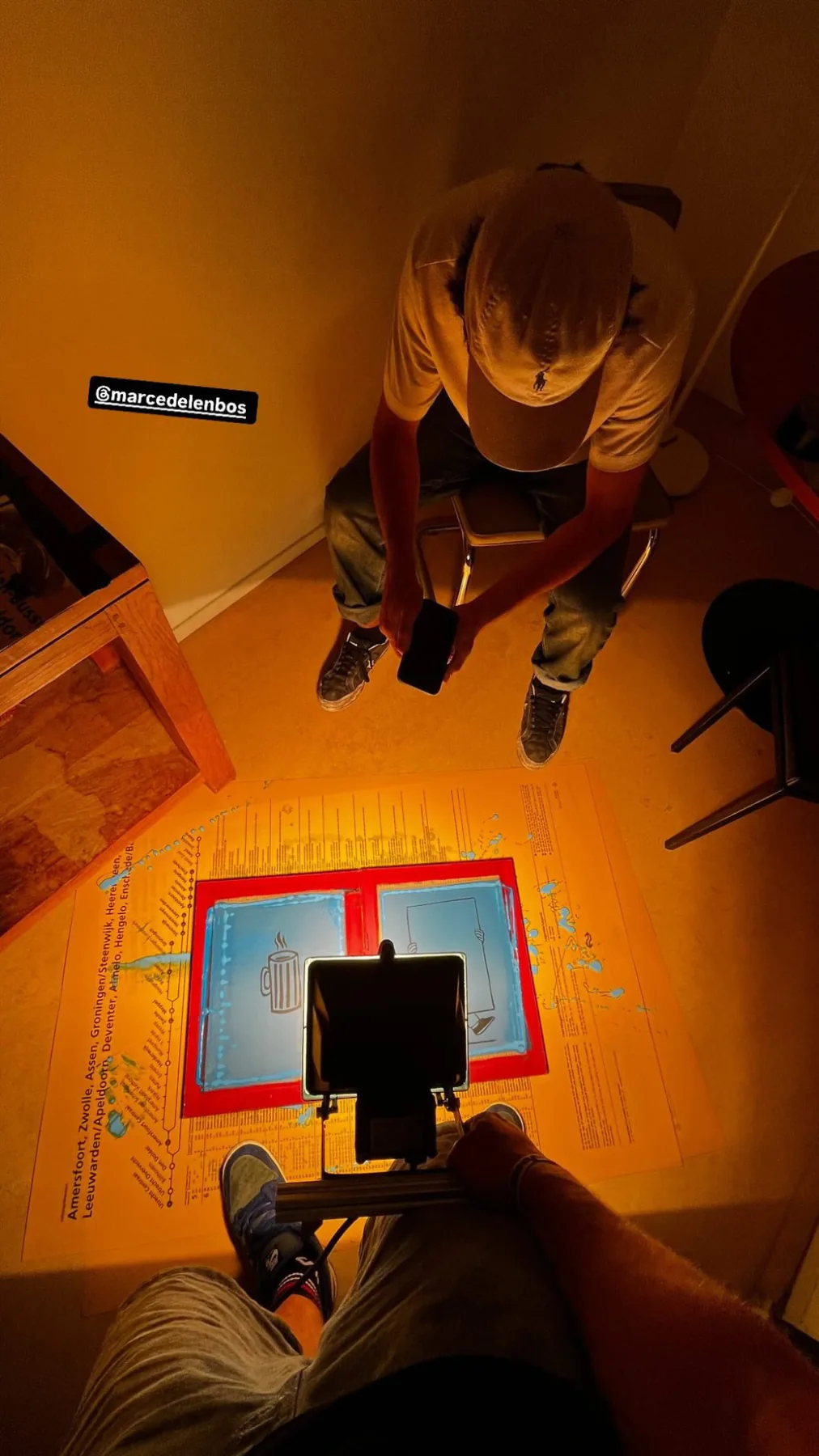 Two people exposing a screen on the floor under warm orange light